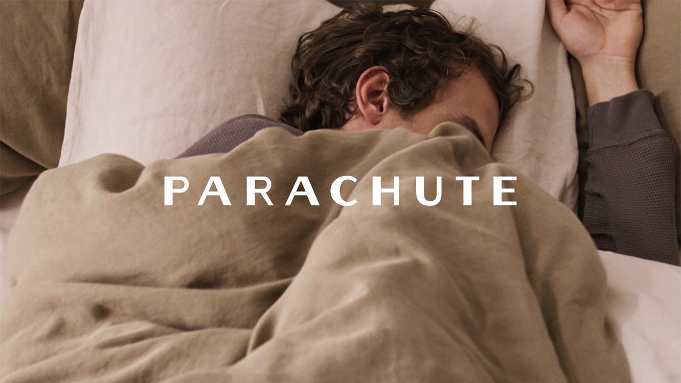 A man in bed under a tan Parachute duvet.