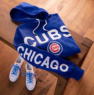 Chicago Cubs MLB team sweatshirt on a wooden table with a pair of sneakers underneath.