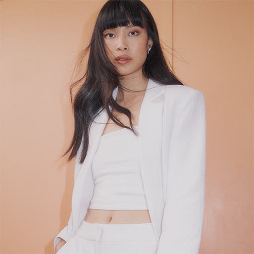 A model in a white suit jacket and crop top.
