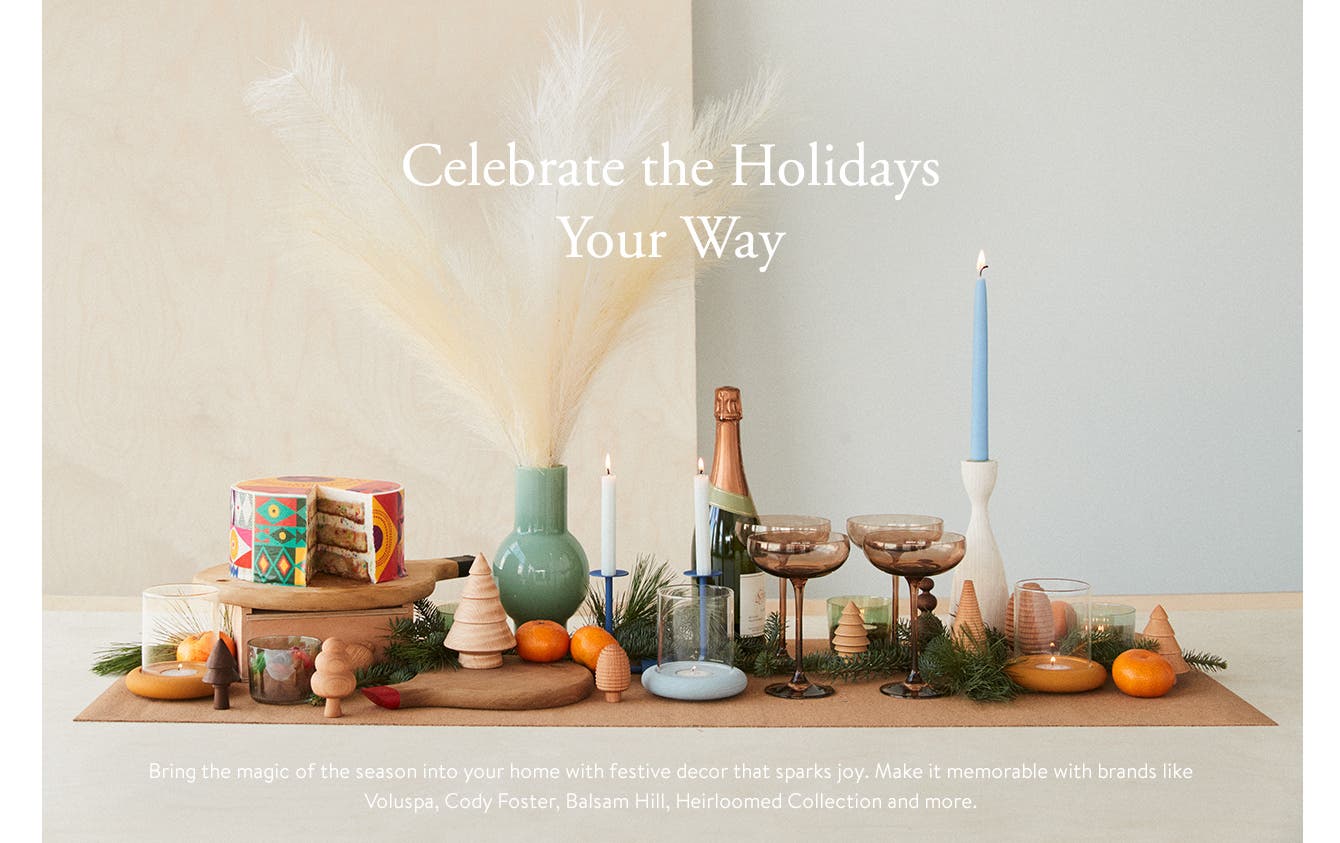 Celebrate the Holidays Your Way. Bring the magic of the season into your home with festive decor that sparks joy. Make it memorable with brands like Voluspa, Cody Foster, Balsam Hill, Heirloomed Collection and more.
A table setting with candles, glassware, cake and fruit, greenery and wooden Christmas trees.