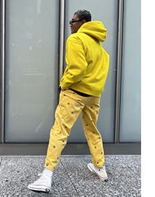 A man wearing a yellow hoodie with yellow pants.