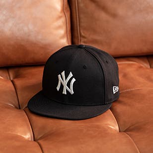 MLB New York Yankees hat on a leather couch.