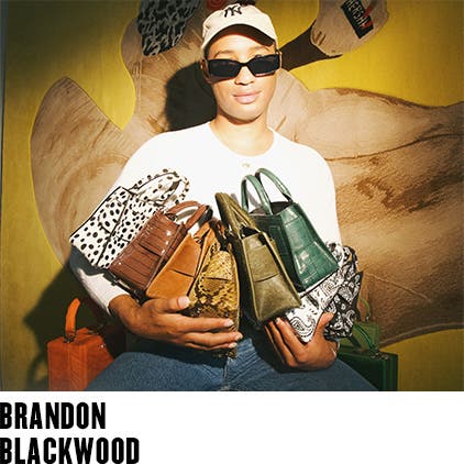 Brandon Blackwood holding handbags from his line.