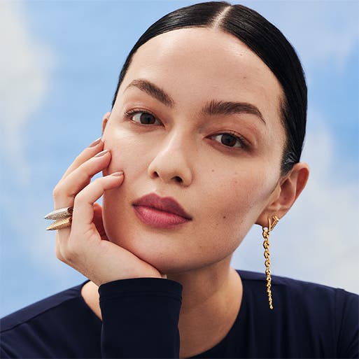 A woman wearing bold statement earrings and rings.