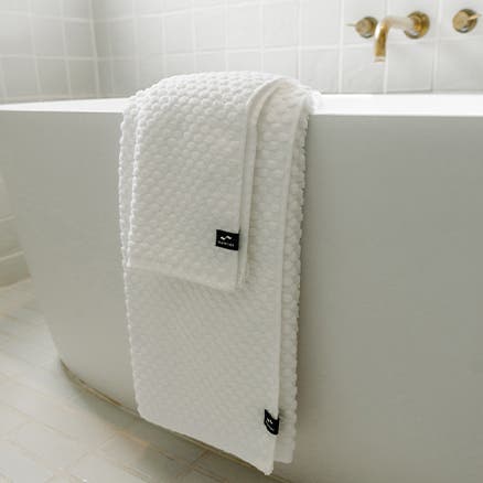 White towels draped on the side of a bathtub.