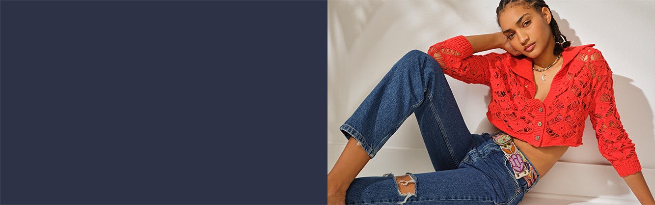A woman wearing a red top and blue jeans from Free People.