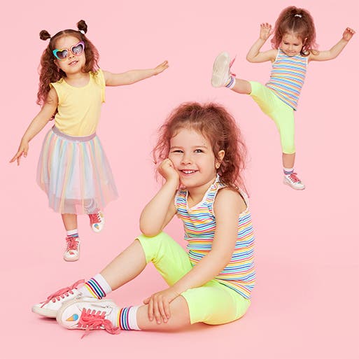A little girl wearing a top and skirt with sneakers. A little girl wearing a tank top, leggings and sneakers.