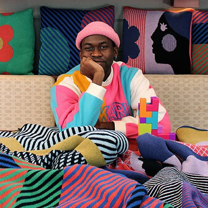 A man with vibrantly colored throw blankets and accent pillows.