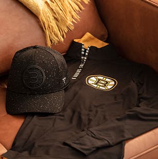 Bruins NHL team hat and long-sleeve shirt on a leather couch.