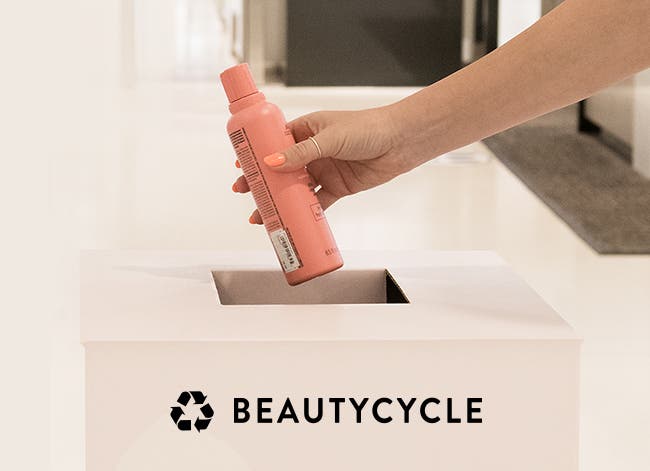An empty shampoo bottle being placed in a BEAUTYCYCLE bin.