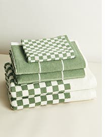 A stack of towels with green and white checkerboard and stripe patterns.