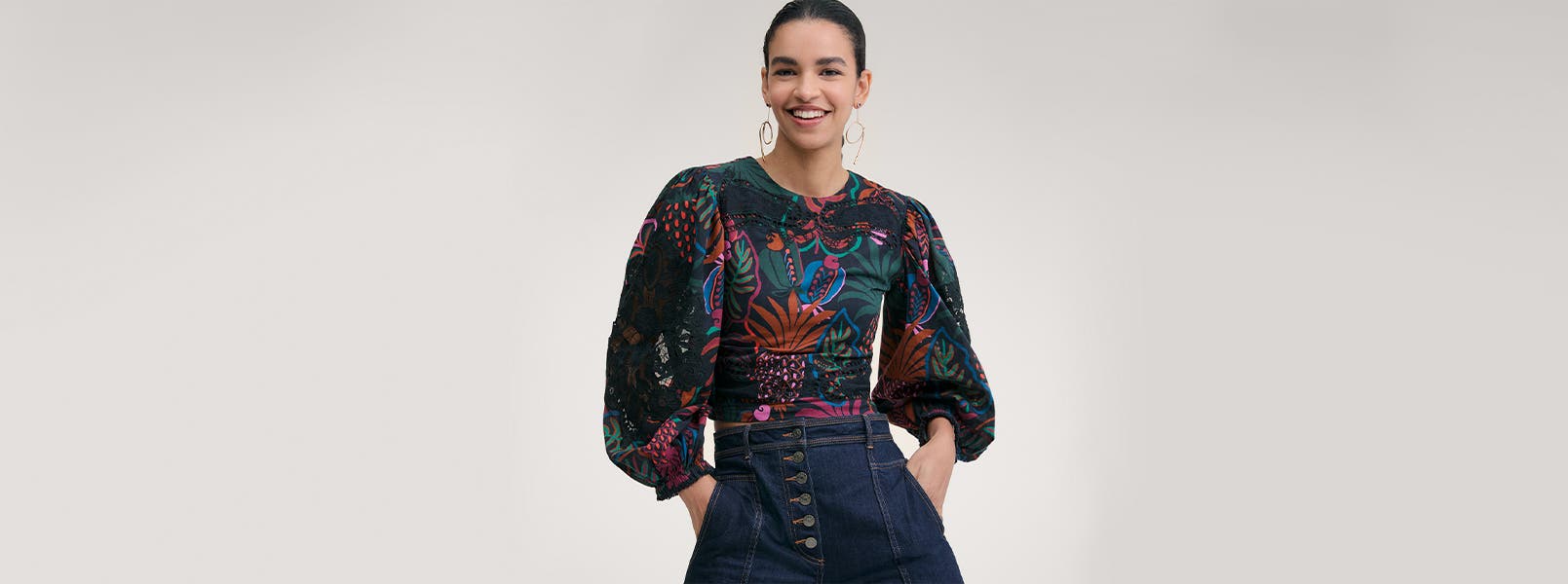 A woman wearing a printed blouse and denim pants.
