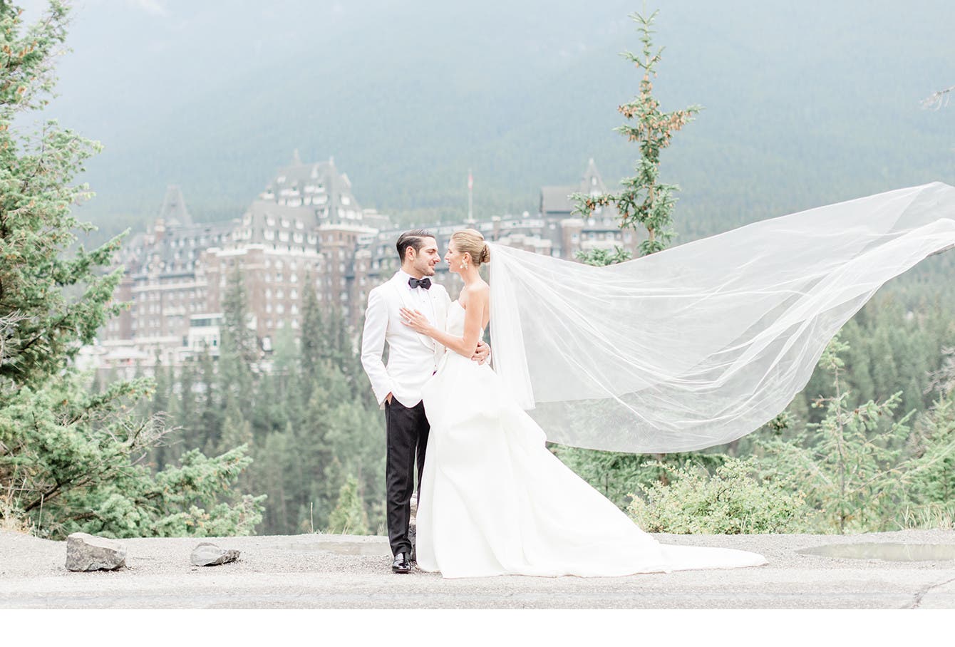Newlyweds Holly and Abraham pose before a castle in the Canadian wilderness.