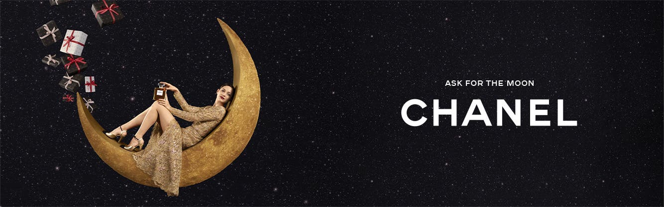 Ask for the moon. An image of a woman reclining inside a crescent moon with a large bottle of CHANEL perfume and many wrapped gifts.