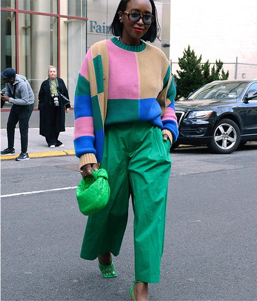 A woman wearing green pants and a color-blocked sweater.
