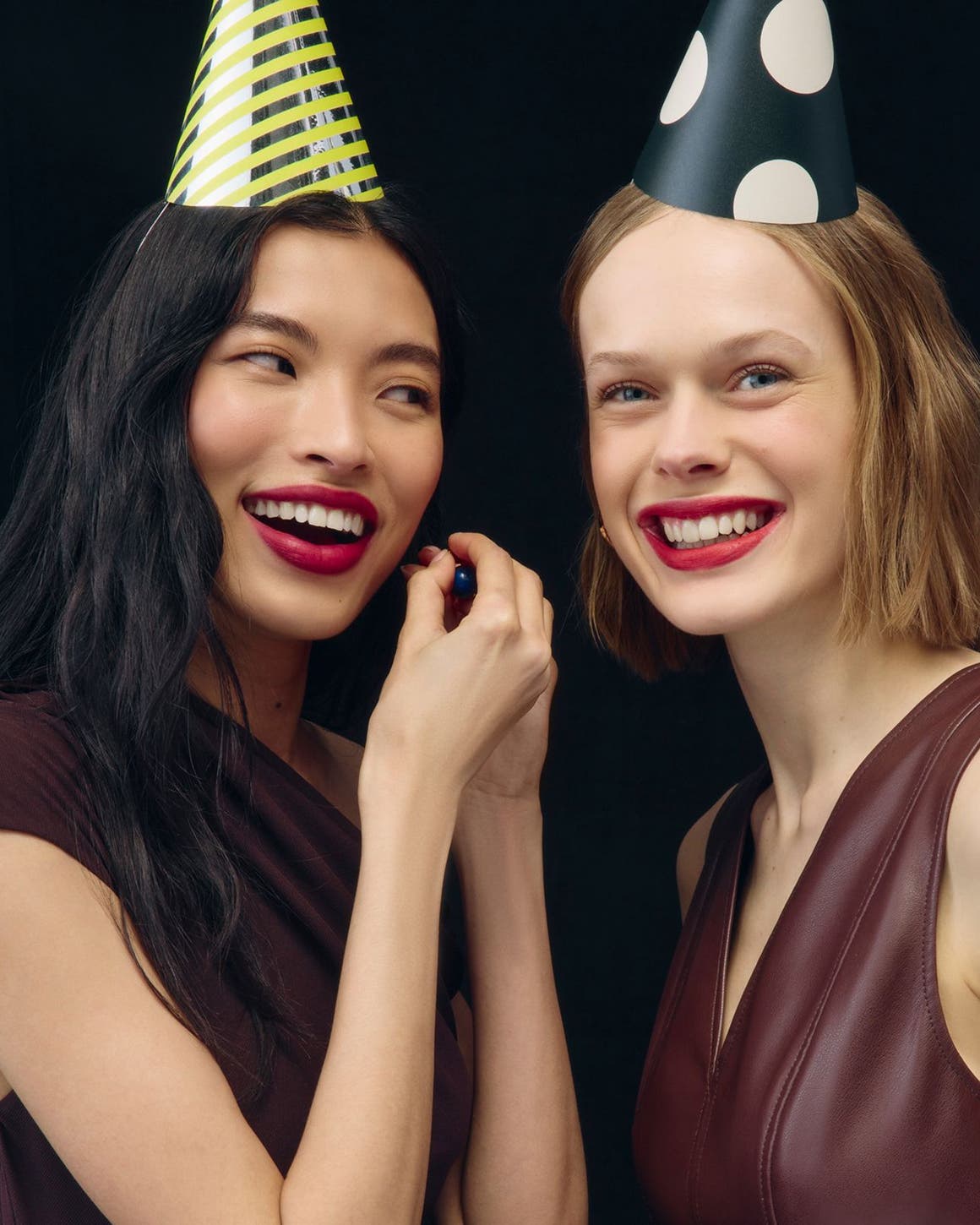 Women wearing makeup and party hats.