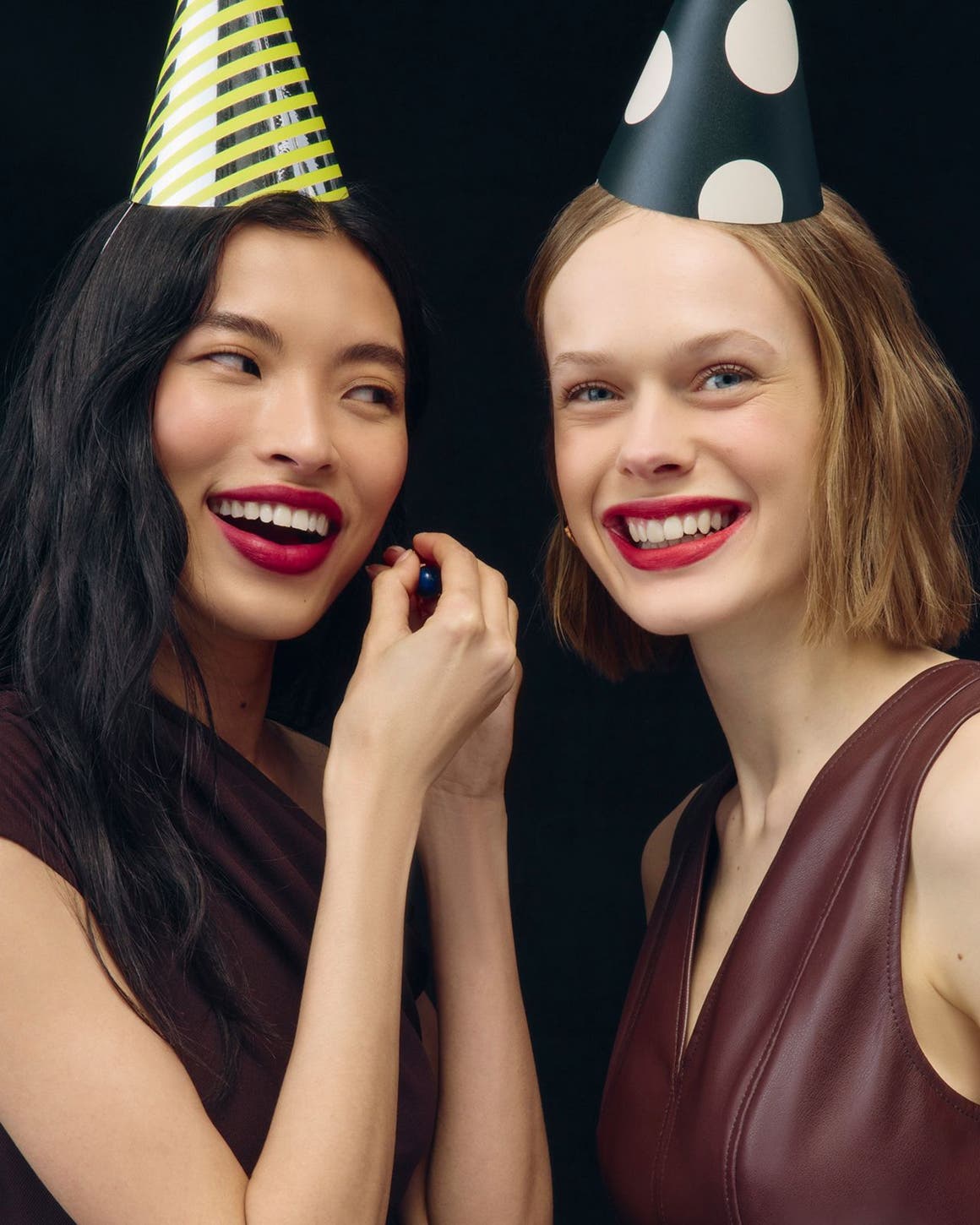 Women wearing makeup and party hats.