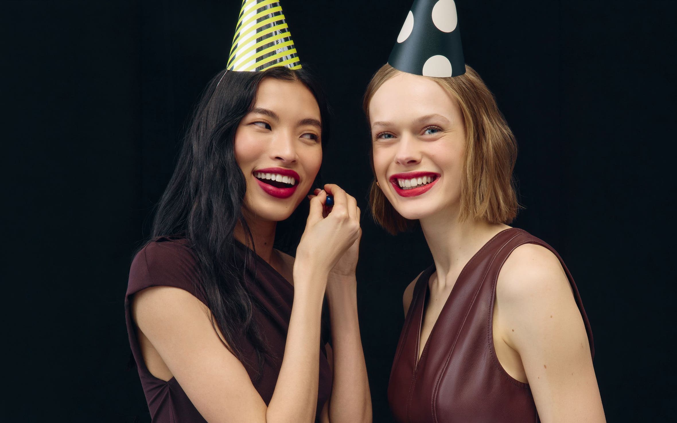 Women wearing makeup and party hats.