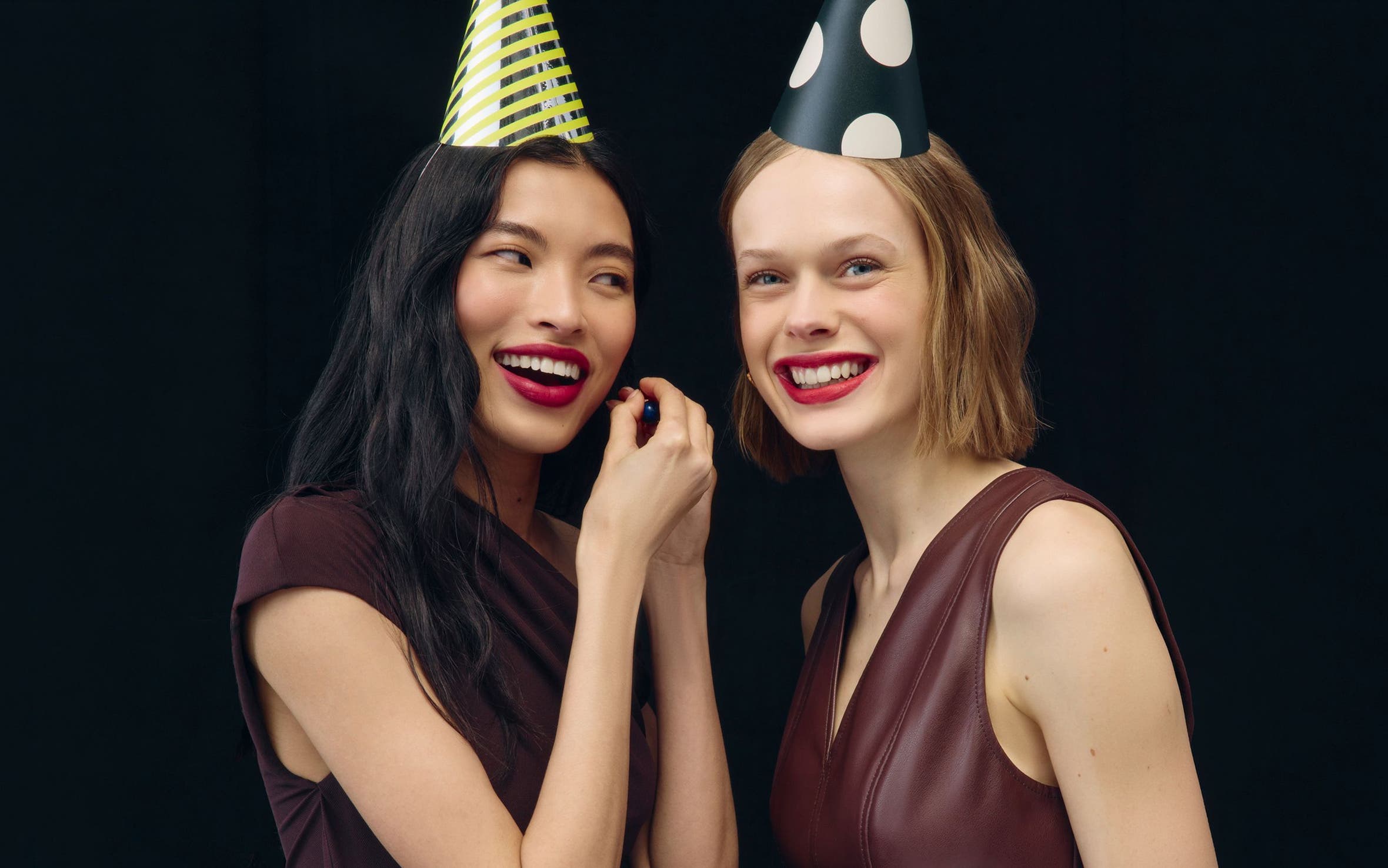 Women wearing makeup and party hats.