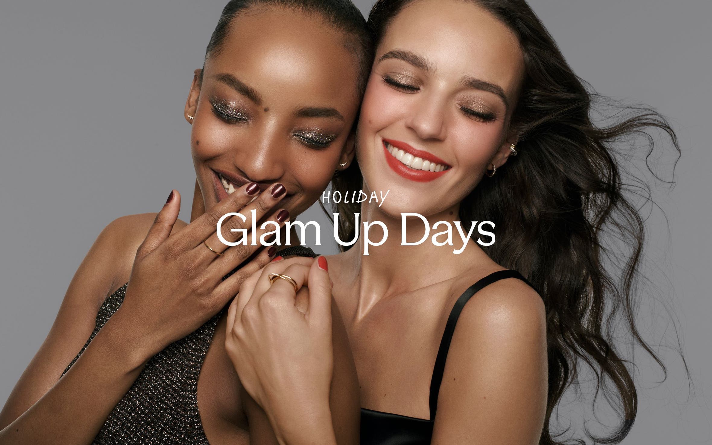 Holiday Glam Up Days; two women in glam makeup and jewelry laughing together.