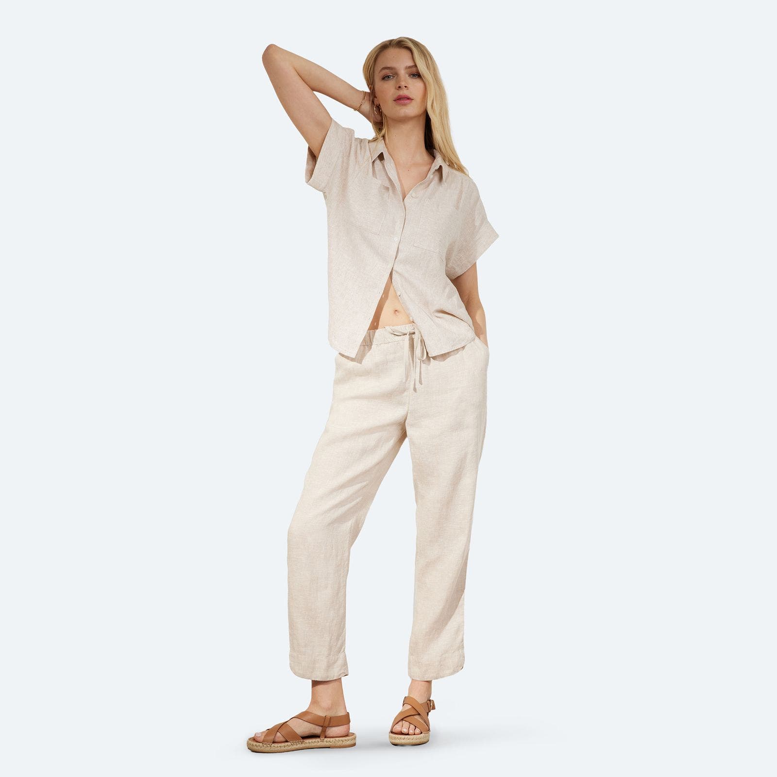 A woman in a neutral linen pant and matching button-up shirt. 