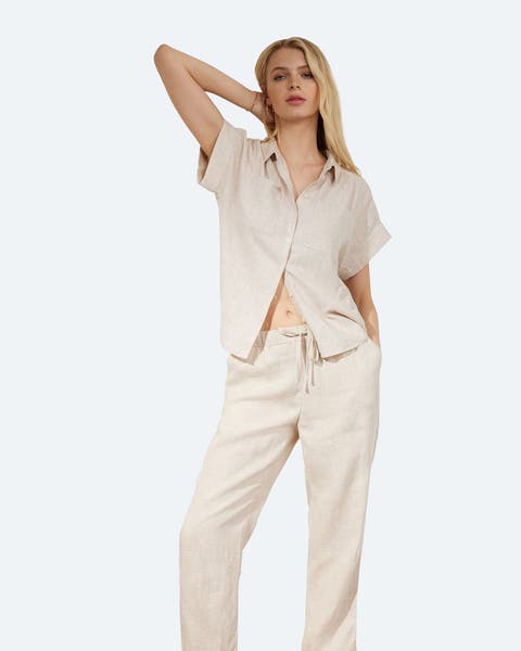 A woman in a neutral linen pant and matching button-up shirt.