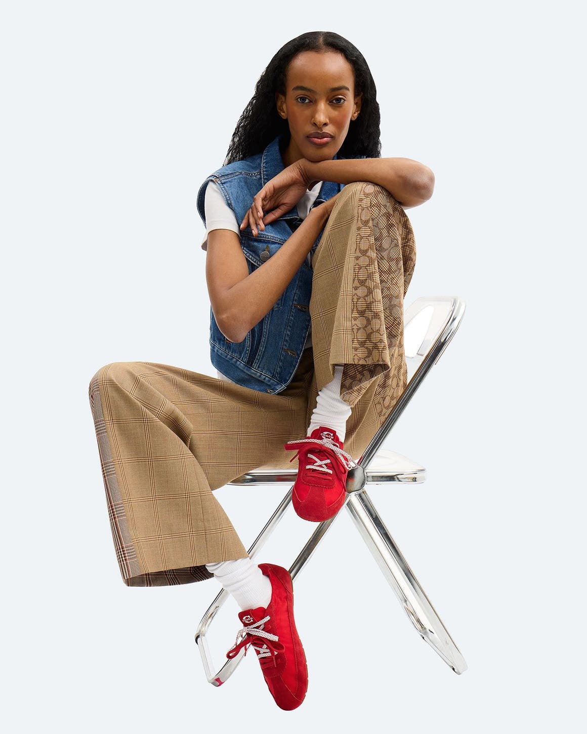 A girl sitting on a chair wearing red COACH sneakers with double laces