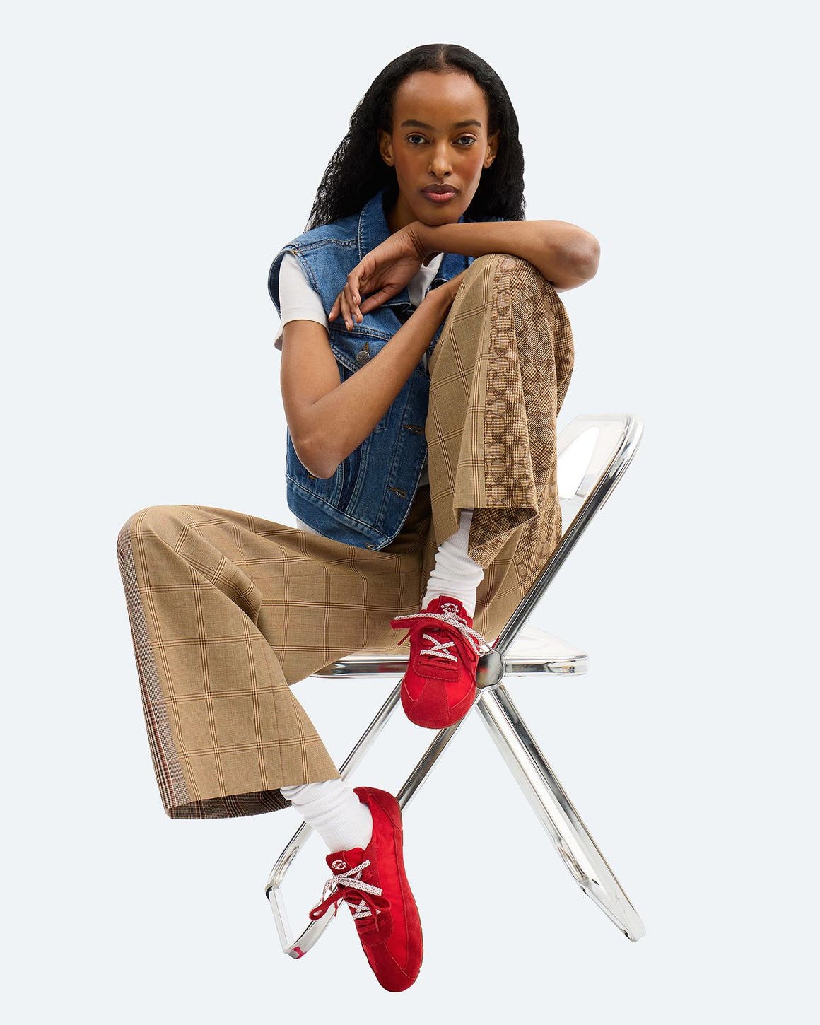 A girl sitting on a chair wearing red COACH sneakers with double laces