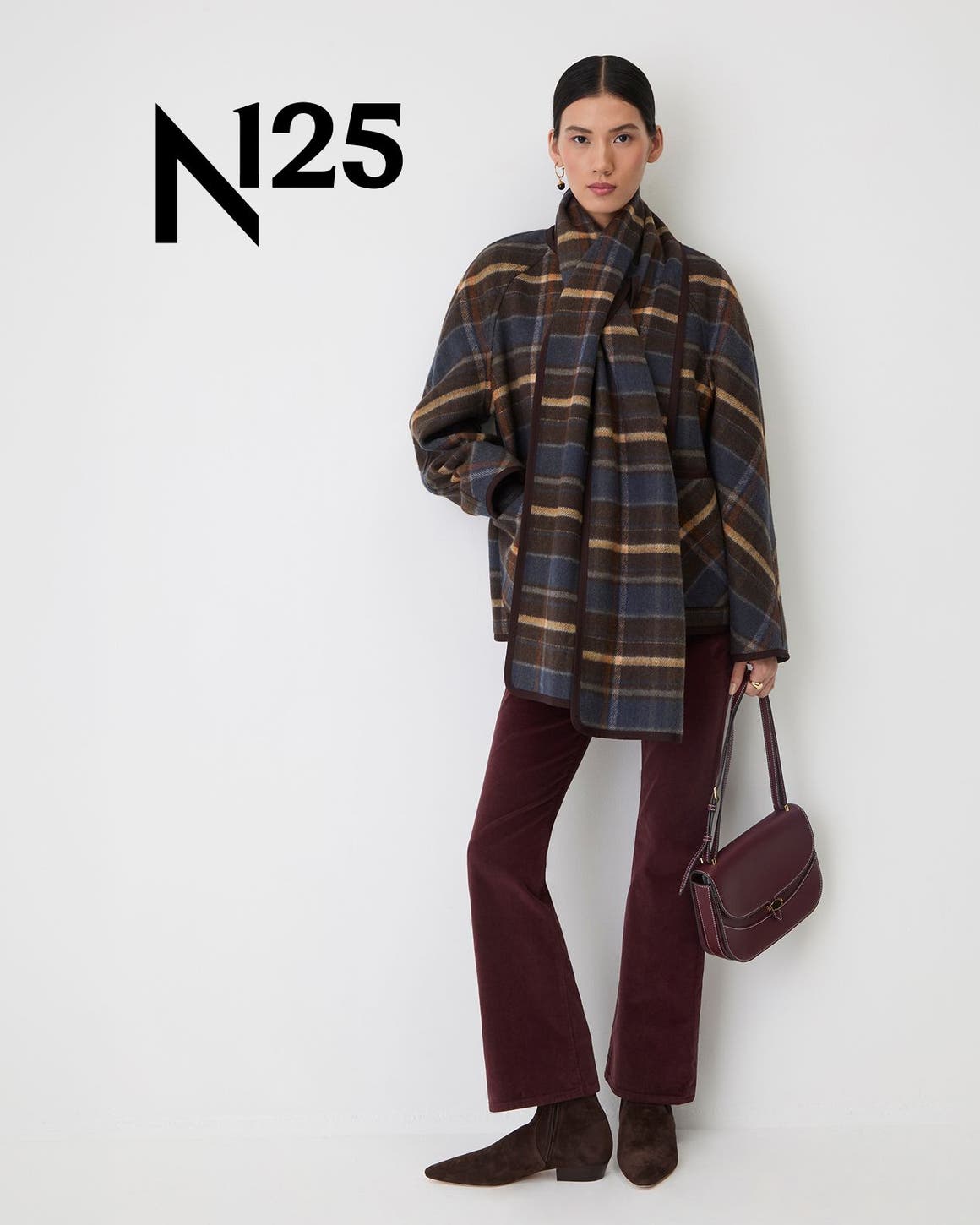 A woman wearing a plaid shacket with a matching scarf and corduroy pants.