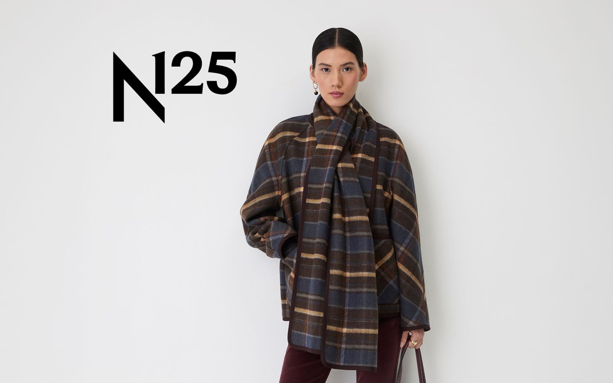 A woman wearing a plaid shacket with a matching scarf and corduroy pants.