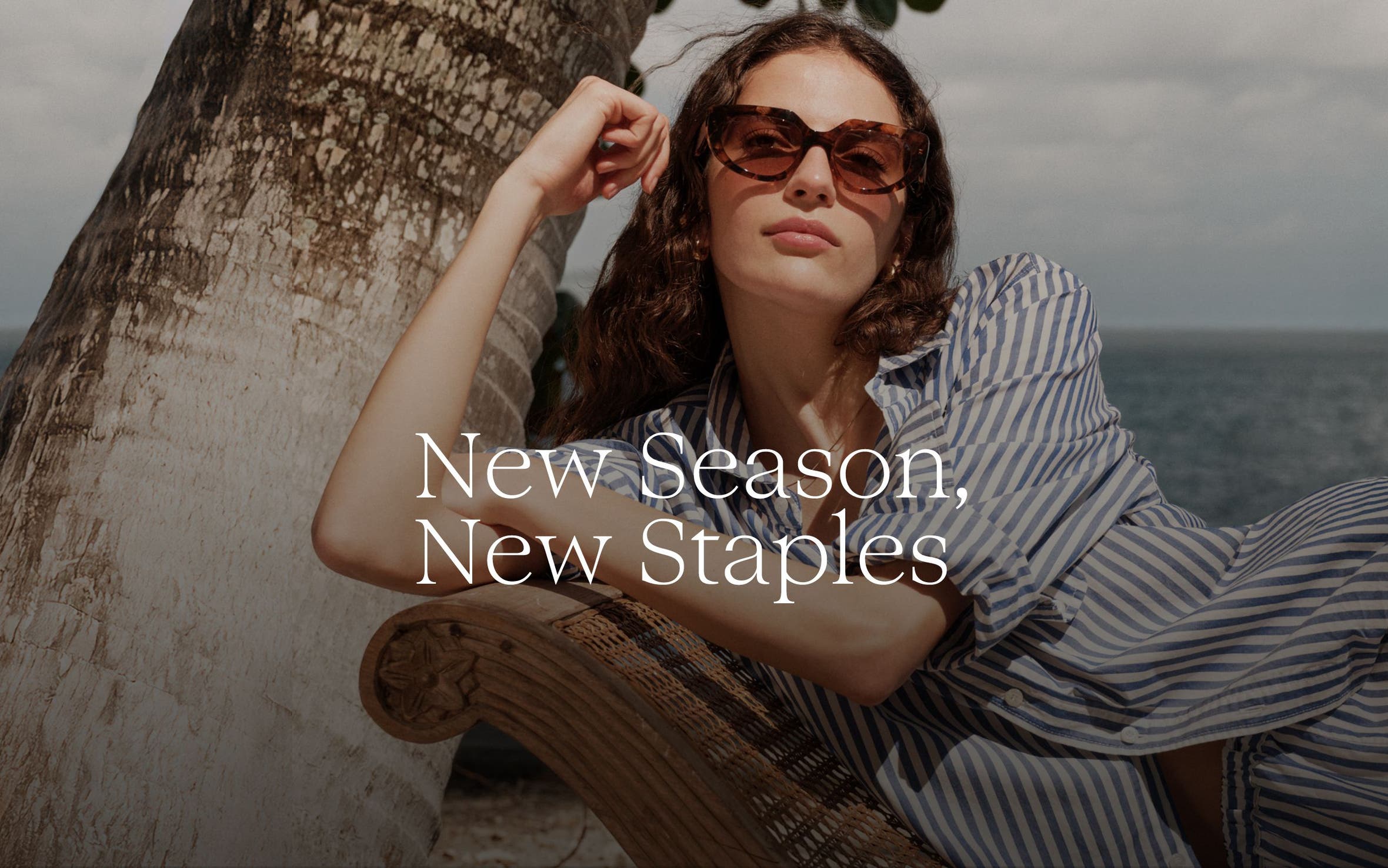 New Season, New Staples. Woman in a striped outfit and sunglasses at the beach.