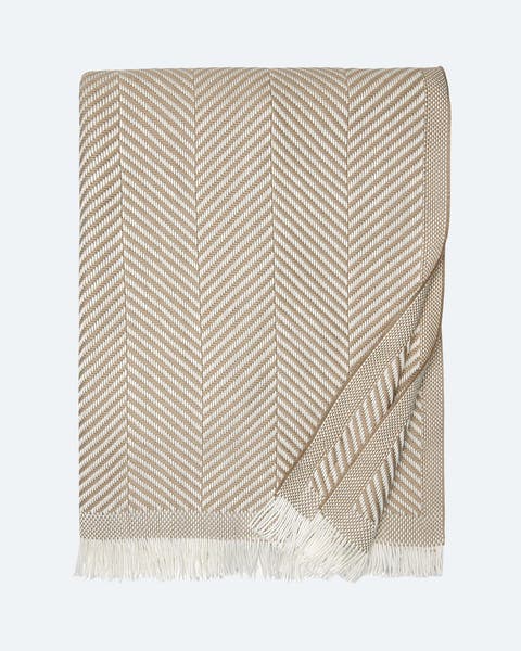 A tan and white herringbone cotton throw blanket.