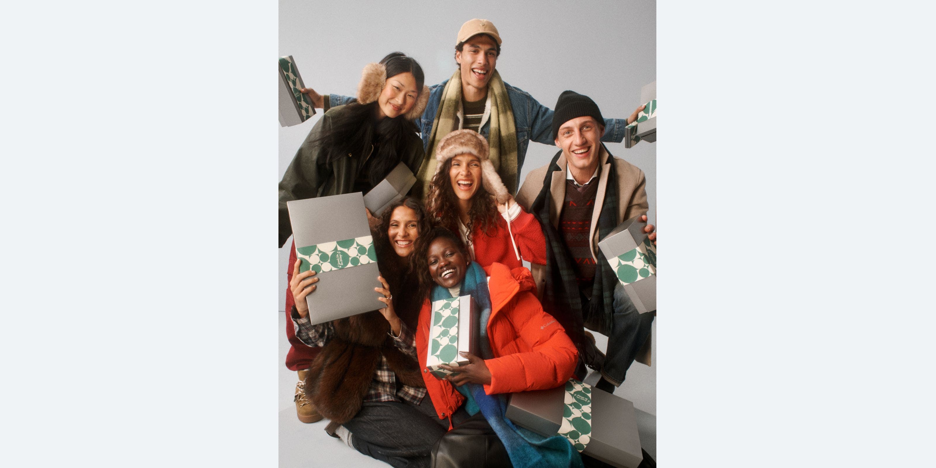 A group of people bundled up holding silver Nordstrom holiday gift boxes.