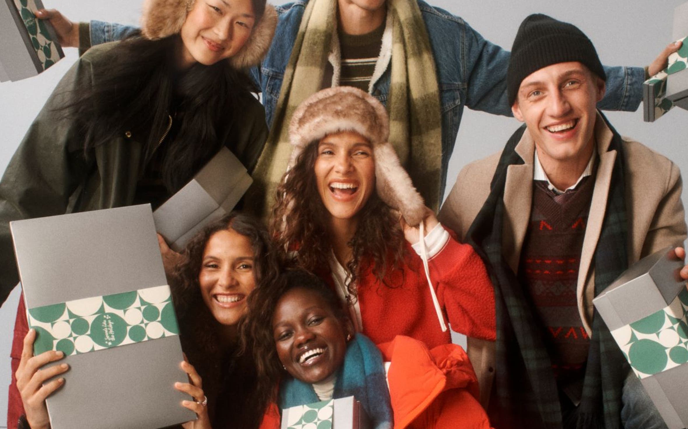 A group of people bundled up holding silver Nordstrom holiday gift boxes.