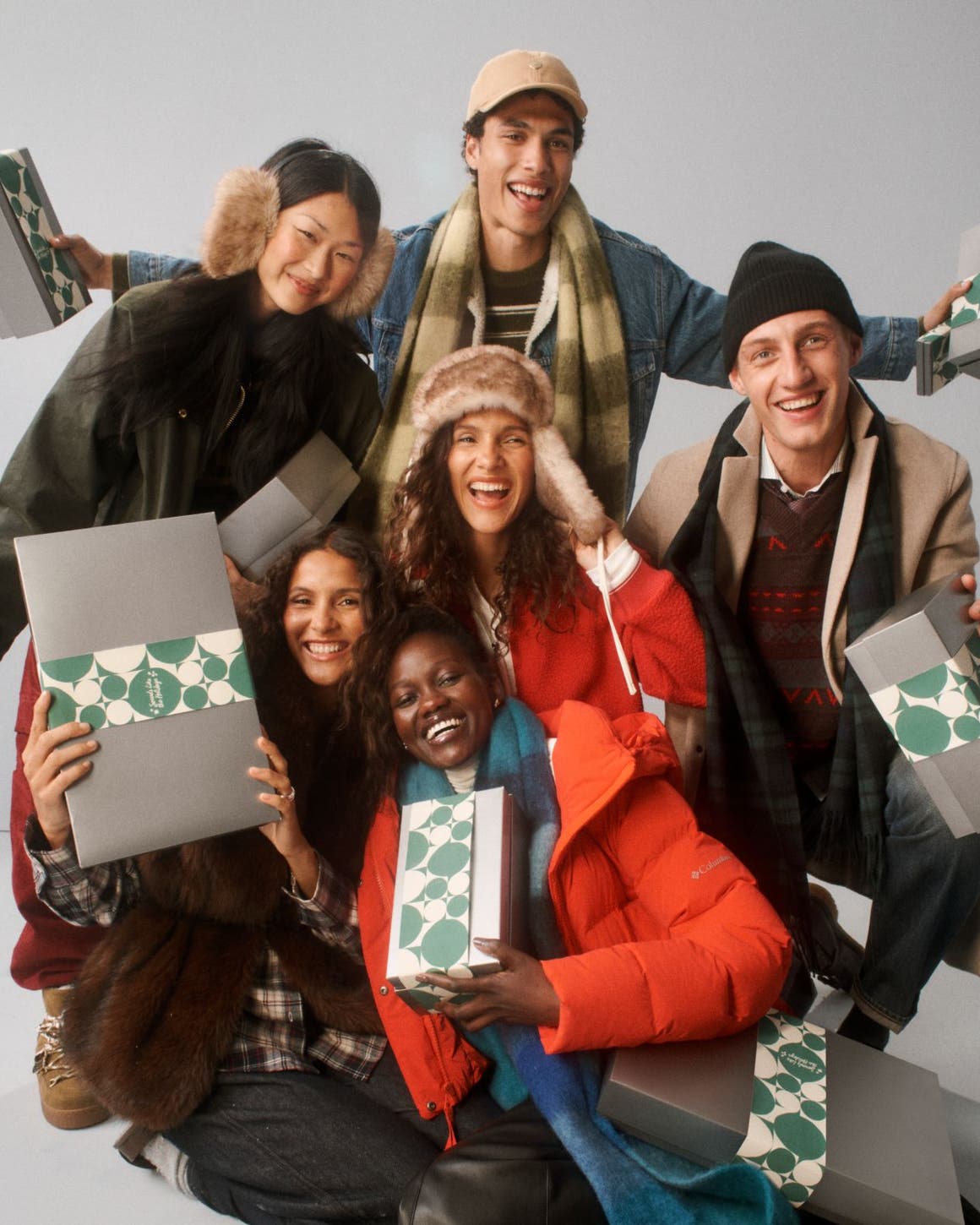A group of people bundled up holding silver Nordstrom holiday gift boxes.