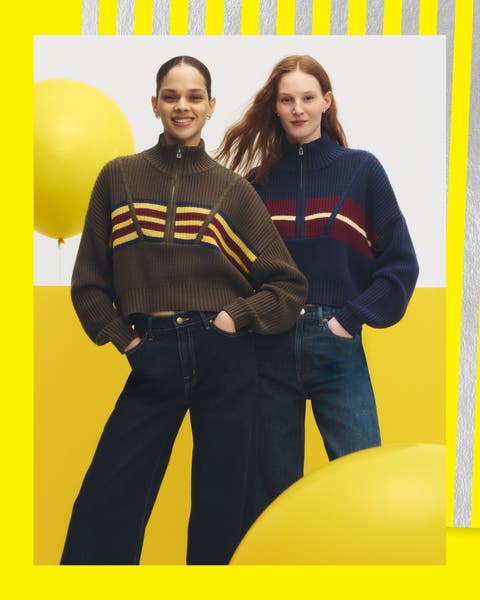 Two women wearing matching sweaters and jeans.