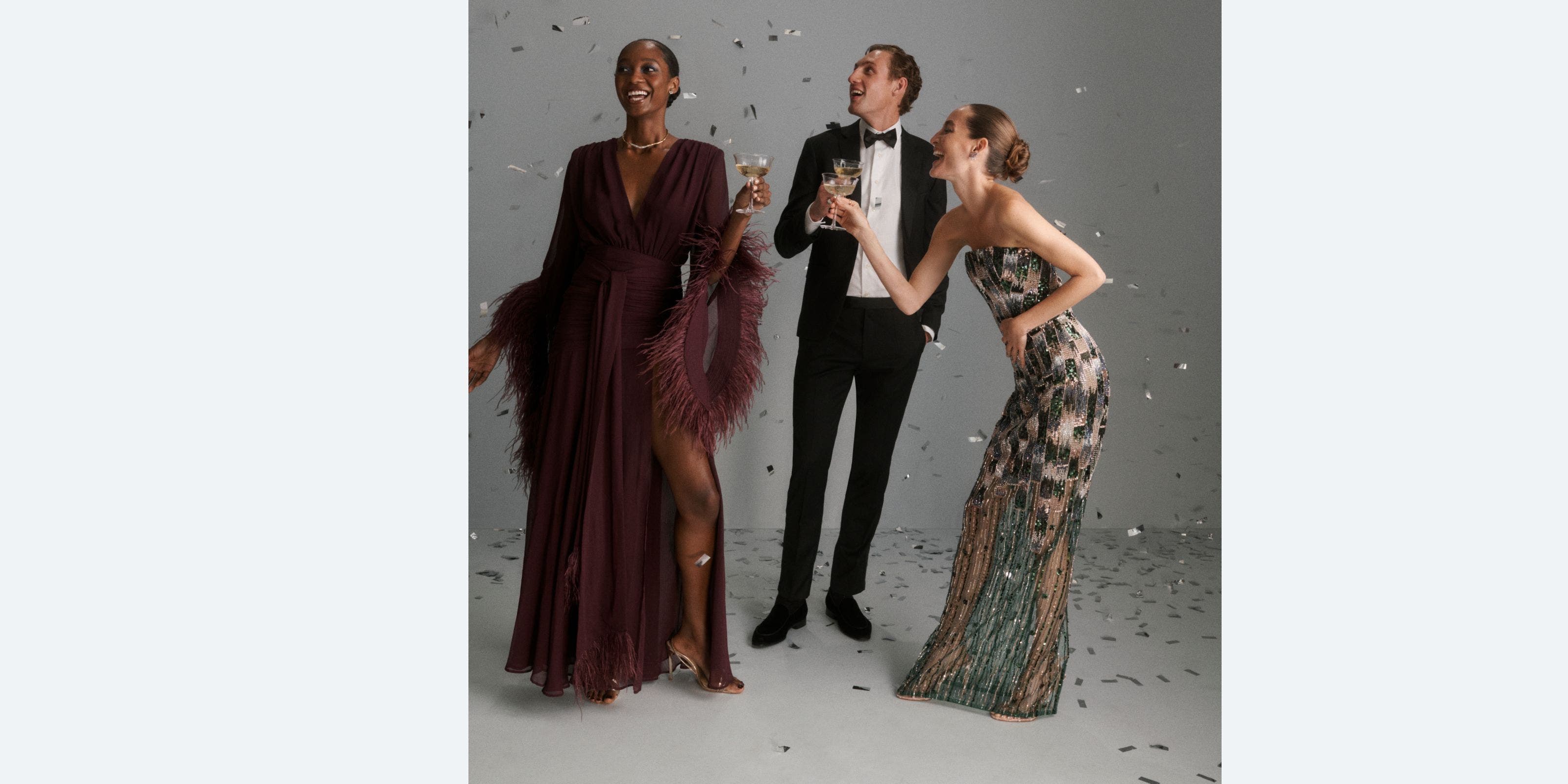 A group of people in formal dress throwing confetti and drinking champagne. 