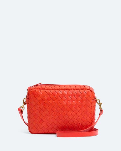 Red woven leather crossbody bag with an adjustable strap.