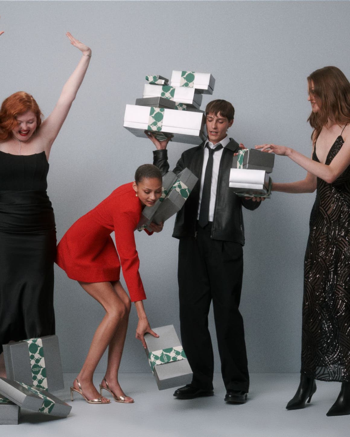 A group of people in formal dress holding silver Nordstrom gift boxes.
