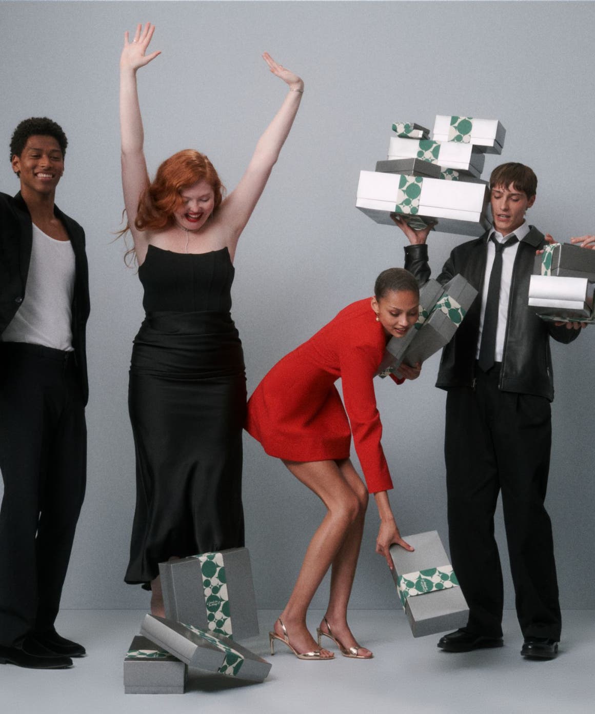A group of people in formal dress holding silver Nordstrom gift boxes.