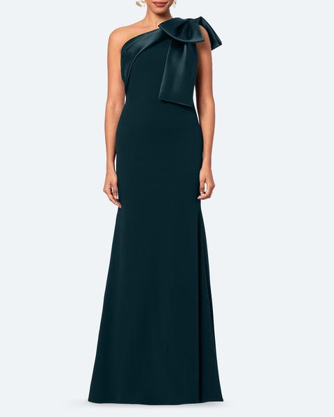 A woman wearing a one shoulder emerald green gown with big shoulder bow.