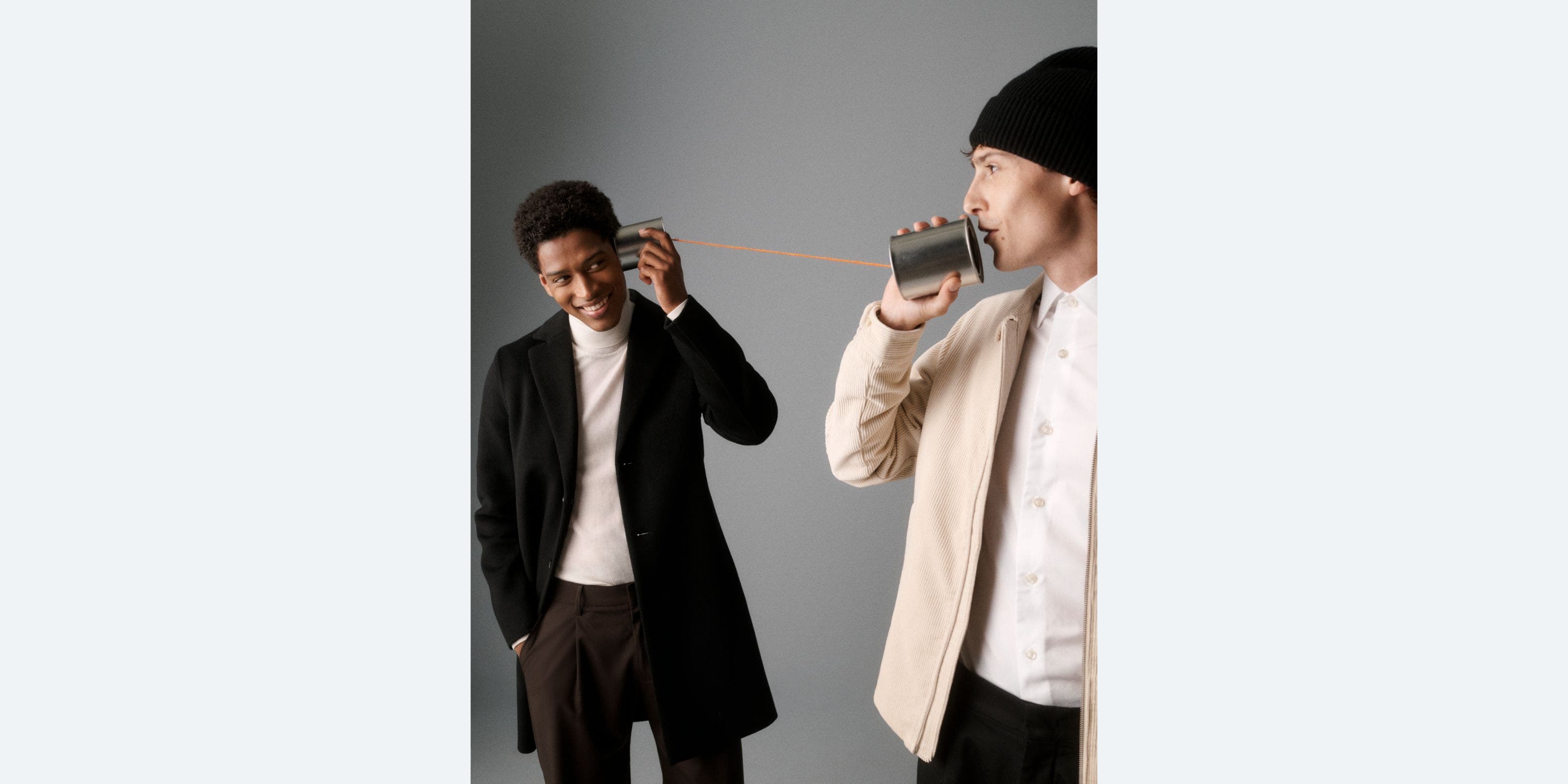 Two men holding a tin can phone.