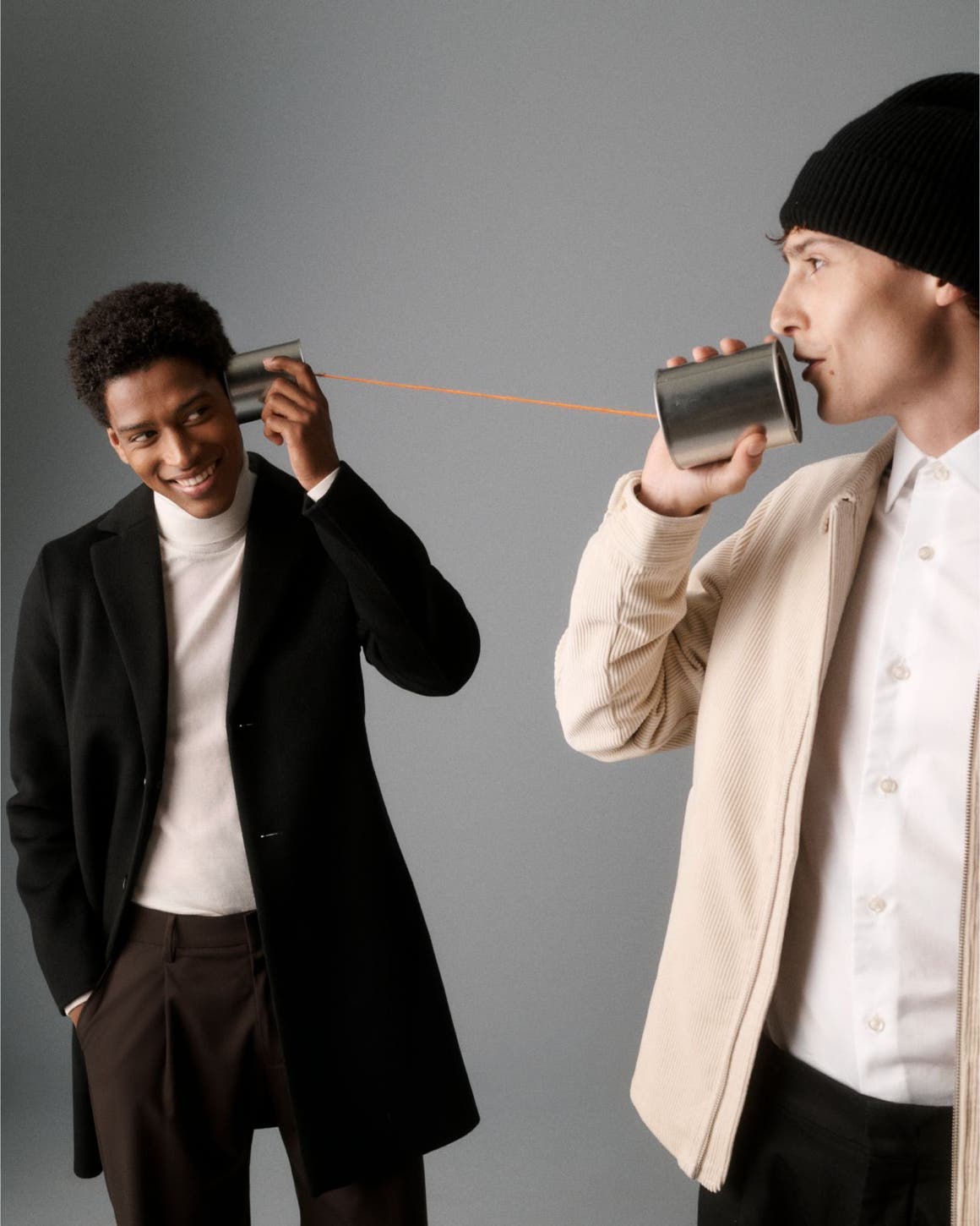 Two men holding a tin can phone.