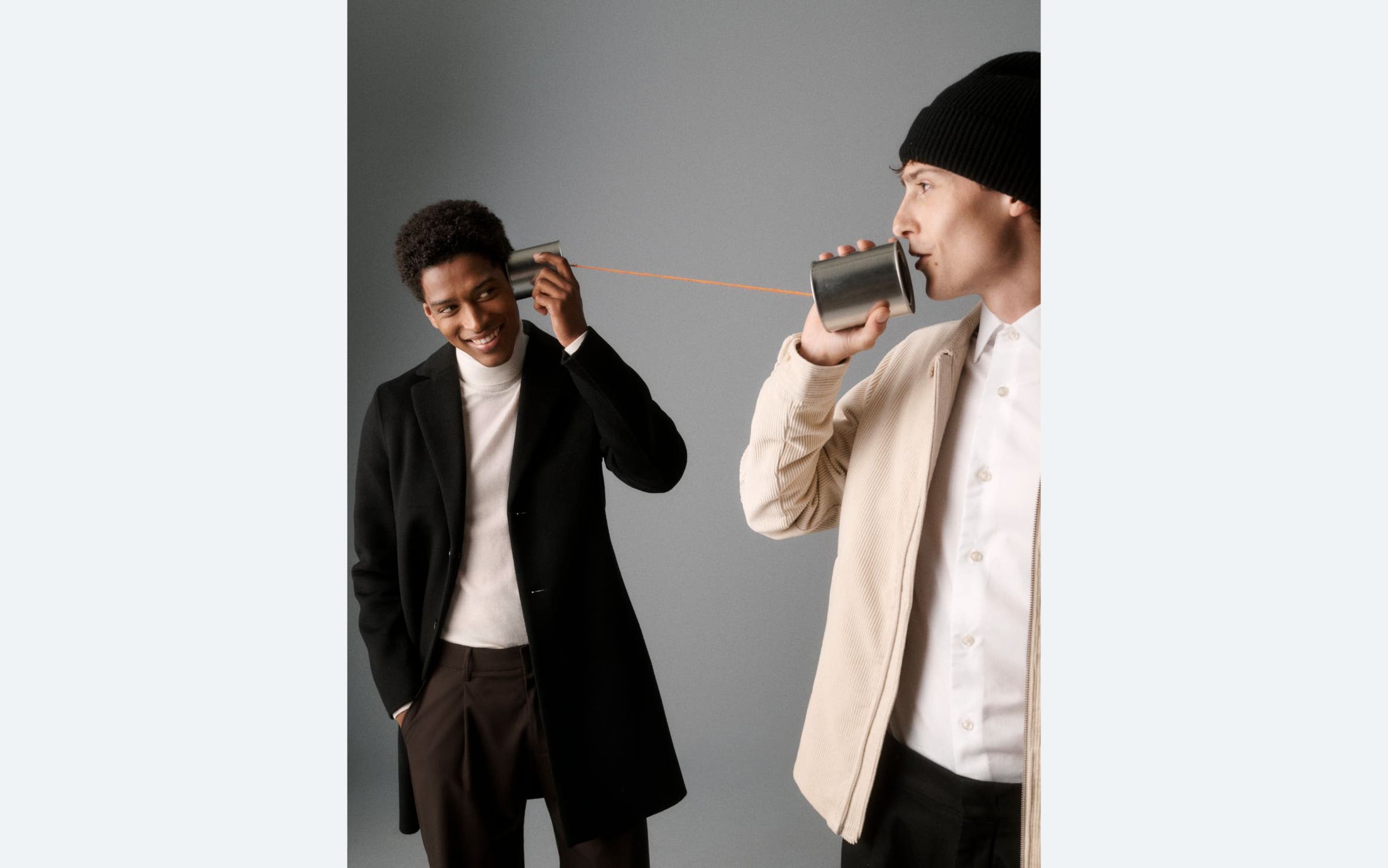 Two men holding a tin can phone.