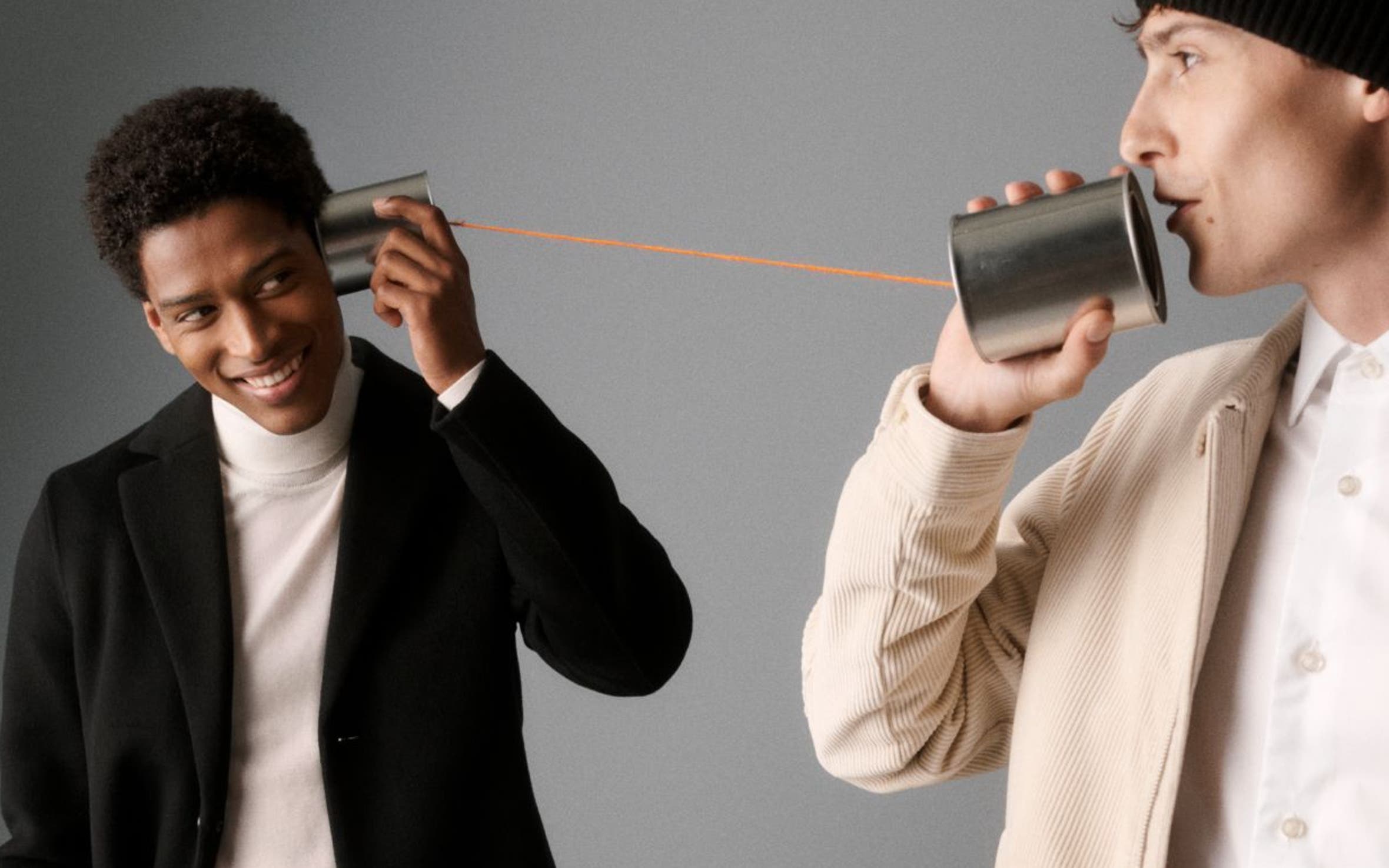 Two men holding a tin can phone.