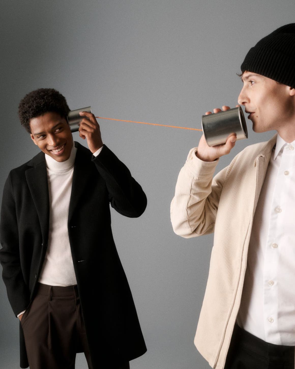 Two men holding a tin can phone.