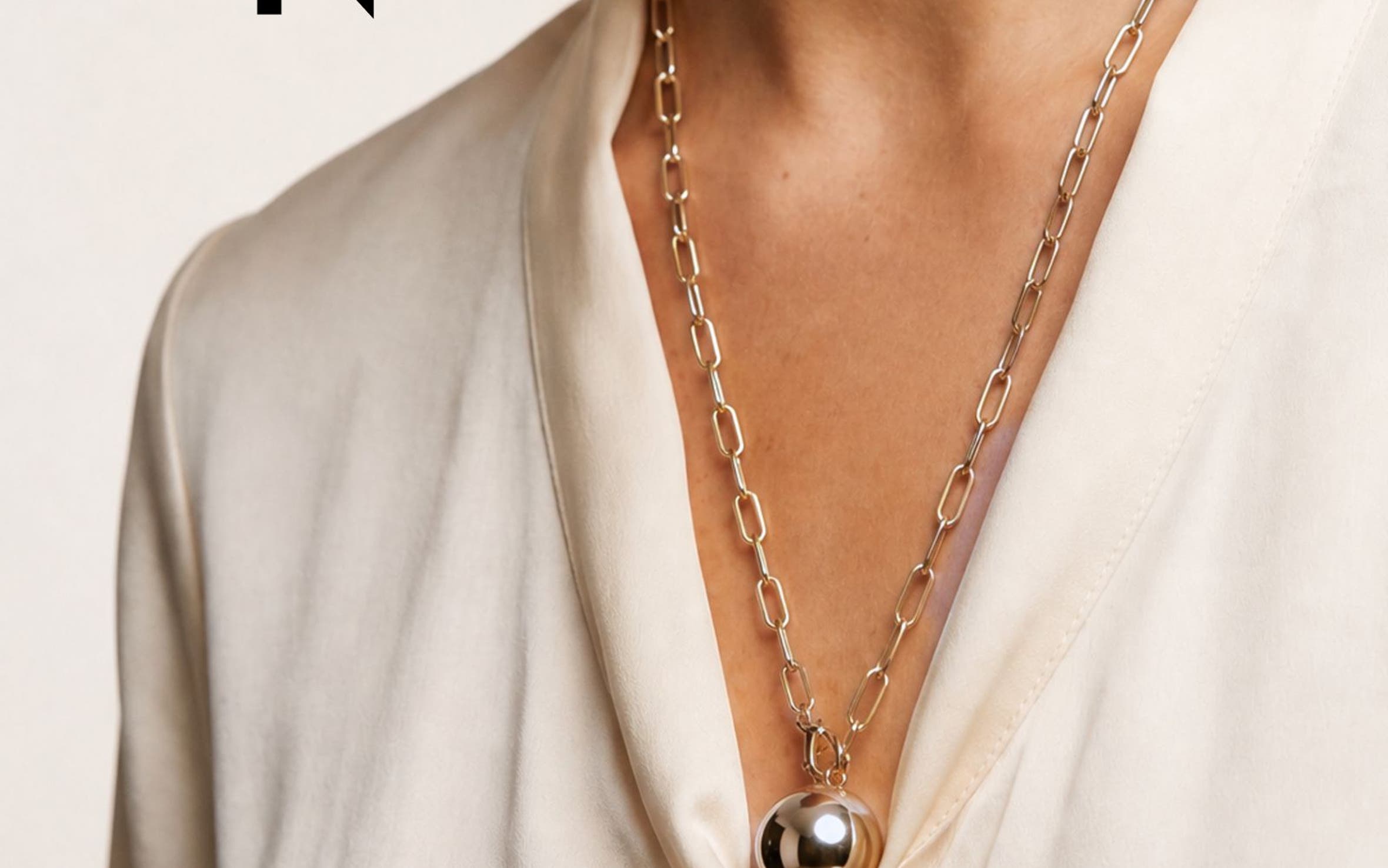 A woman wearing a gold chain necklace.