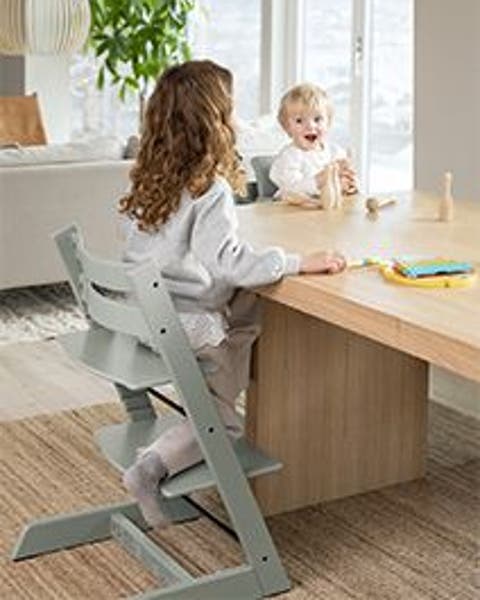 A small child in a high chair at a dining table.