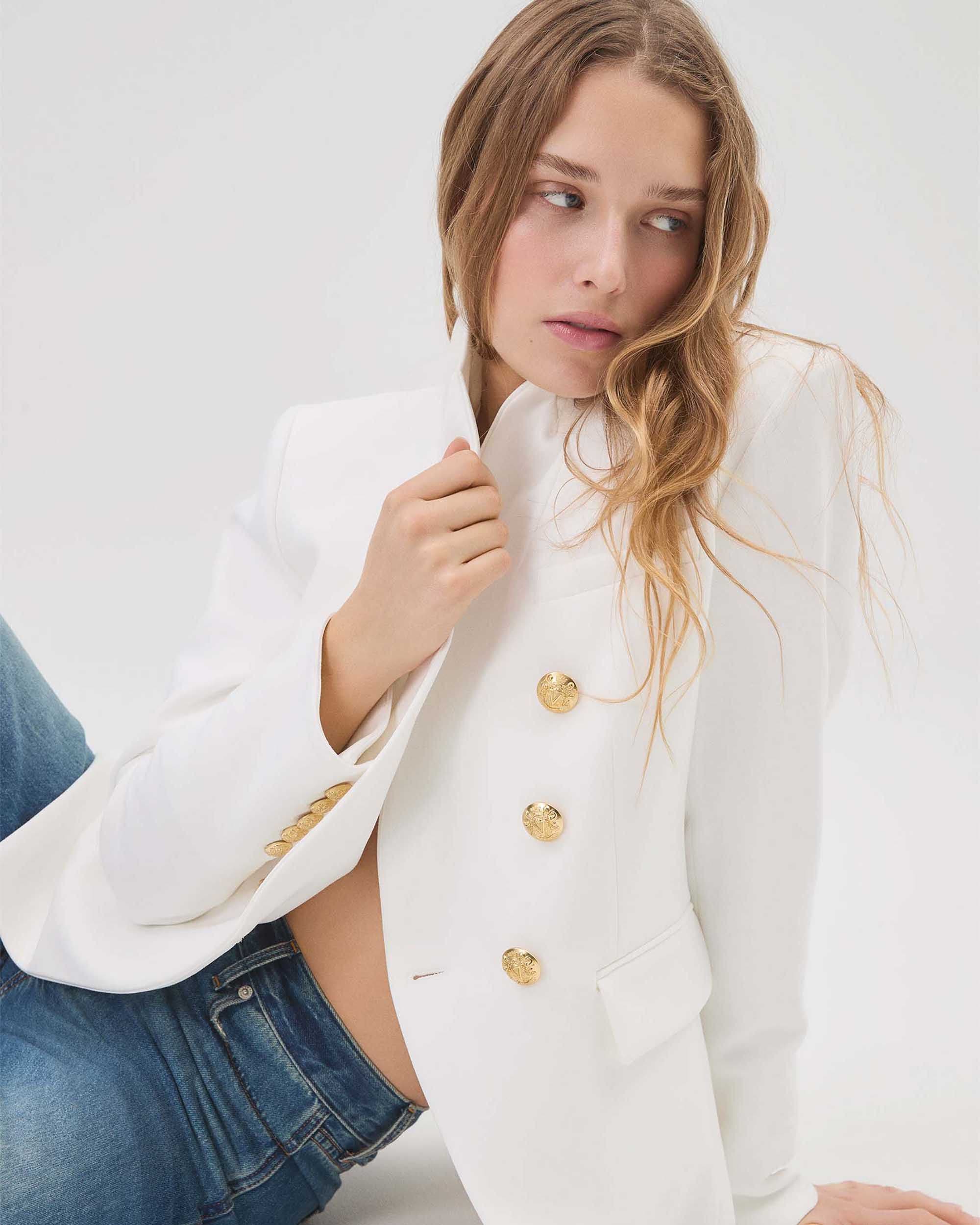 Woman wearing a white Veronica Beard blazer with jeans.
