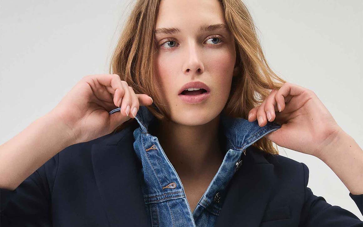 Woman wearing a navy Veronica Beard blazer with a denim dickey.